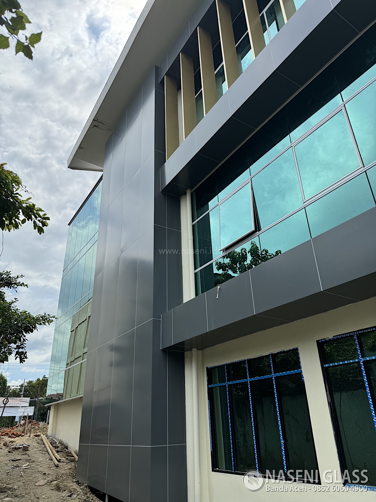 Fasad kaca modern Gedung PERKIM Aceh dengan pencahayaan alami maksimal